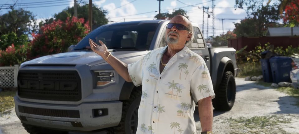 Brian Heder in a tropical shirt gesturing in front of a silver Caracara pickup