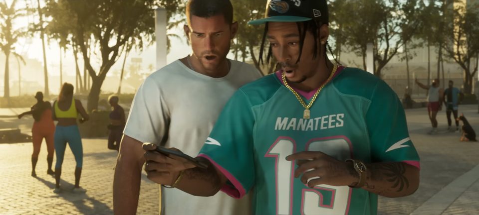 Dre'Quan Priest in a teal Manatees jersey reacting to a phone video with Jason